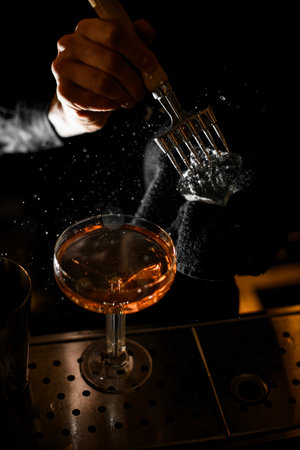 Male hands of a bartender crushing a piece of ice with a special ice pickの写真素材