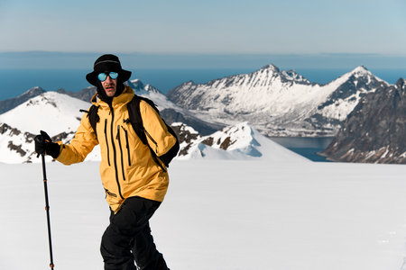 Close-up of a skier in a yellow jacket with one arm, skiing, holding a pole in one handの写真素材