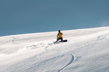 One-armed splitboarder maneuvers his splitboard down a snowy mountainsideの写真素材