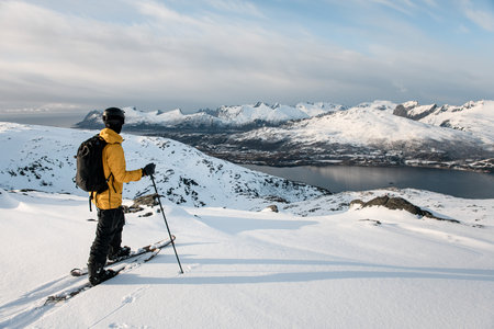 Skier tourist reached the mountain river on skis and admires the beautiful mountain landscapeの写真素材