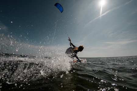 Girl rides on a surfboard on the waves of the sea with a parachuteの写真素材