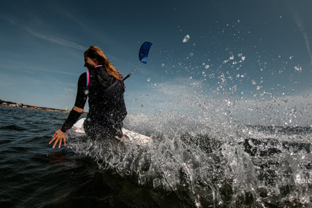 Back view of a girl sits on a board for surf with a parachute on backgroundの写真素材