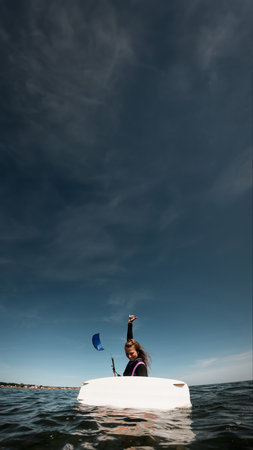 Girl in a water near a white surfboard with orange letteringの写真素材