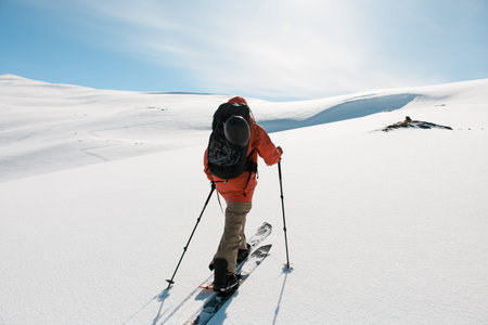 Photo from the back of a skier climbing a snowy mountain slope
