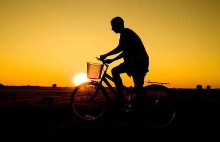Man and  bike  silhouette in orange sunriseの写真素材