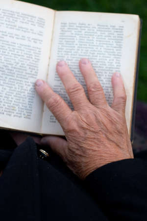  Senior's hands on old bookの写真素材