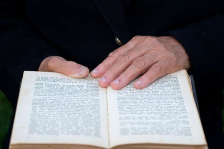  Senior's hands on old bookの写真素材