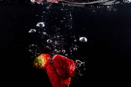 splashing strawberry into a waterの写真素材