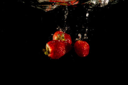 splashing strawberry into a waterの写真素材