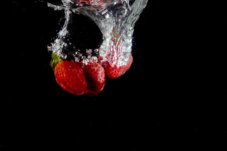 splashing strawberry into a waterの写真素材