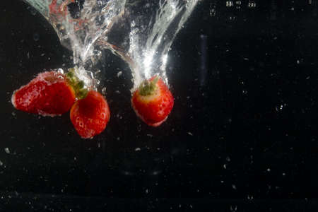 splashing strawberry into a waterの写真素材