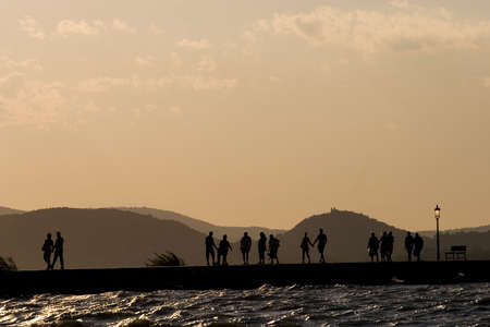 people walking in the sunset on the moleの写真素材