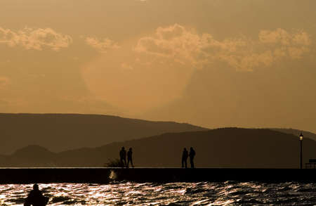 people walking in the sunset on the moleの写真素材
