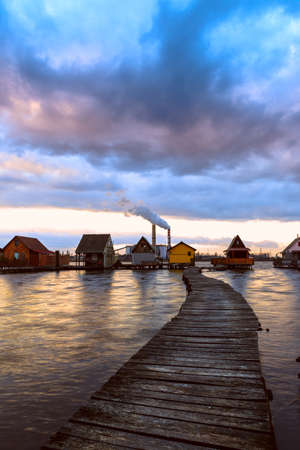 Sunset lake Bokod with pier and fishing wooden cottages, power plant in background, Hungaryの写真素材