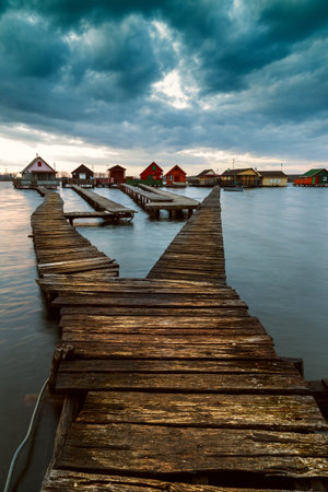 Sunset lake Bokod with pier and fishing wooden cottages, power plant in background, Hungaryの写真素材