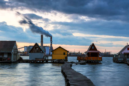 Sunset lake Bokod with pier and fishing wooden cottages, power plant in background, Hungaryの写真素材