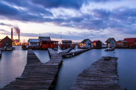 Sunset lake Bokod with pier and fishing wooden cottages, power plant in background, Hungaryの写真素材