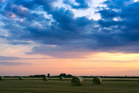 Sunset over farm field with hay bales in Hungary