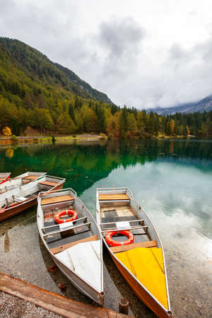 Alpine landscape and colorful boats near Slovenian-Italy border, Lake Fusine,Italyの写真素材