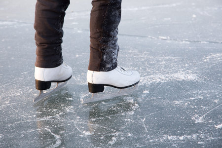 Young woman ice skating outdoors on a pond on a freezing winter day