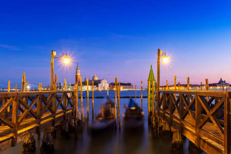 Venice with famous gondolas  in lagoon at sunrise as a background  can see the chucrh of San Giorgio Maggioreの写真素材
