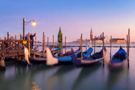 Venice with famous gondolas  in lagoon at sunrise as a background  can see the chucrh of San Giorgio Maggioreの写真素材