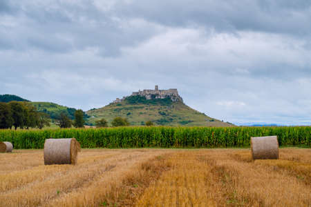 Hay bales on the field after harvest and behind, second biggest castle in Middle Europe - Spis (SpiÅ¡, SpiÅ¡skÃ½) castle in Slovakiaの写真素材