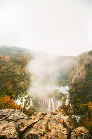 Picturesque autumn waterfall in a calm forest environment in rainy, foggy autumn weather in Plitvice lakesの写真素材
