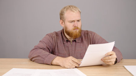 Bearded professional businessman sits at a table with documents in the office. Handsome smart young...