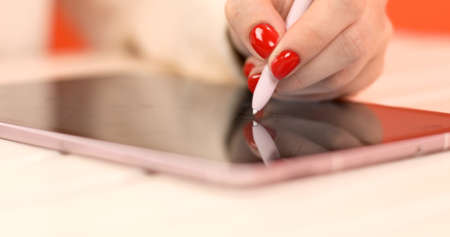 Close-up of a female hand draws with stylus on a tablet device. Modern technologies.の写真素材