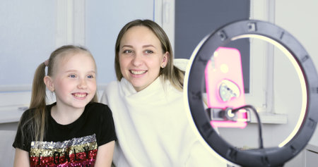 Happy mom and daughter take a selfie on the phone. A woman with a schoolgirl is recording a video...
