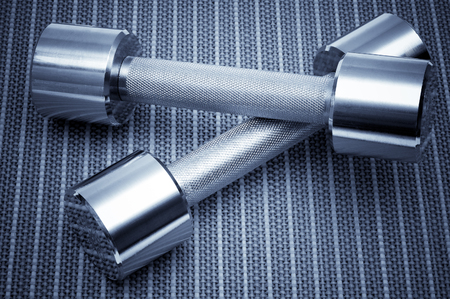 Dumbbells on bamboo mat. Blue tined imageの写真素材