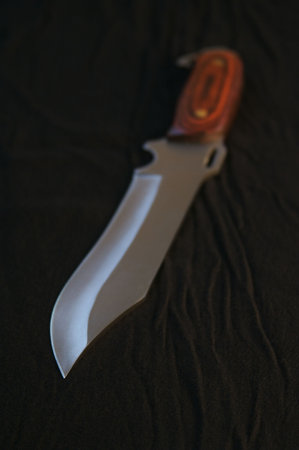 Ominous hunting knife on black background & dramatic lighting.