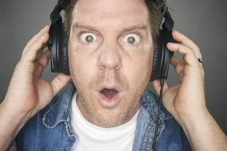 Shocked Man Wearing Headphones against a grey background.の写真素材