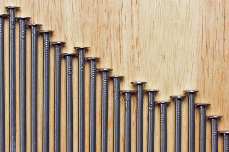 Declining Graph of Nails on a Wood Background.の写真素材