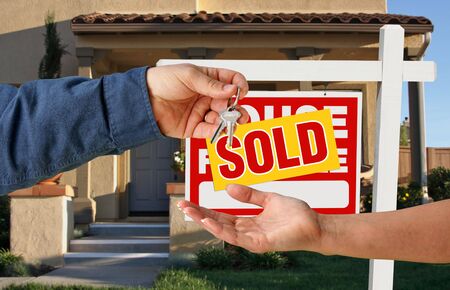 Handing Over the Keys to A New Home with Sold Home For Sale Sign.の写真素材