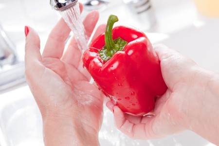 Woman Washing Red Bell Pepper in the Kitchen Sink.の写真素材
