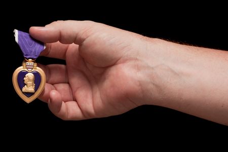 Man Holding Purple Heart War Medal on a Black Background.の写真素材