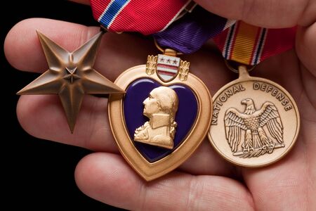 Man Holding Purple Heart, Bronze and National Defense War Medals in The Palm of His Hand.の写真素材