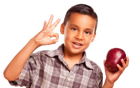 Adorable Hispanic Boy with Apple and Okay Hand Sign Isolated on a White Background.の写真素材