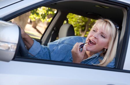 Attractive Woman Putting on Lipstick While Driving.の写真素材