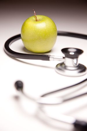 Stethoscope and Green Apple on Gradated Background with Selective Focus.の写真素材