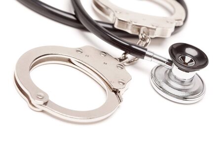 Stethoscope and Handcuffs Isolated on a White Background.の写真素材