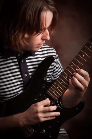 Young Musician Plays His Electric Guitar with Dramatic Lighting.の写真素材