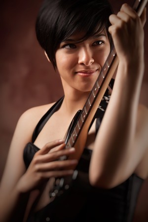 Attractive Multiethnic Girl Plays Her Electric Guitar with Dramatic Lighting.の写真素材