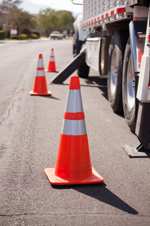 Several Orange Hazard Cones and Utility Truck in Street.