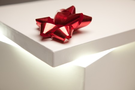 Gift Box with Red Bow Lid Revealing Very Bright Contents on a Gradated Background.の写真素材