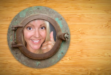 Antique Porthole on Bamboo Wall, Woman with Thumbs Up Looking Through Window.の写真素材