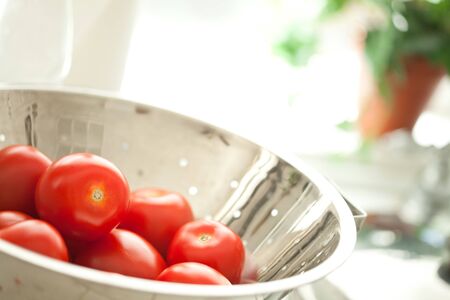 Macro of Fresh, Vibrant Roma Tomatoes in Colander with Water Drops Abstract.の写真素材