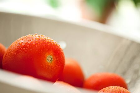Macro of Fresh, Vibrant Roma Tomatoes in Colander with Water Drops Abstract.の写真素材